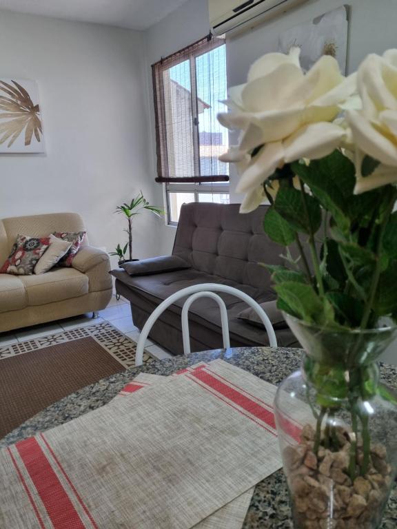 a living room with a vase with white roses in it at Apto 2 quartos, cond fechado, com vaga, 4º andar por escadas in Pelotas