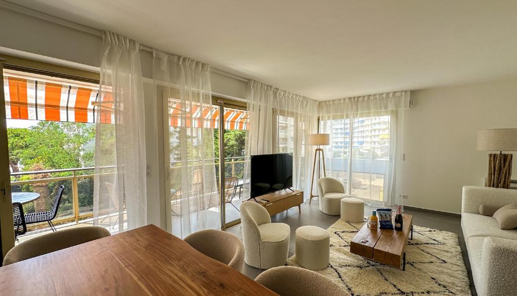 un salon avec une table, des chaises et une télévision dans l'établissement Pointe Croisette, Palais & Palm Beach à pied, à Cannes