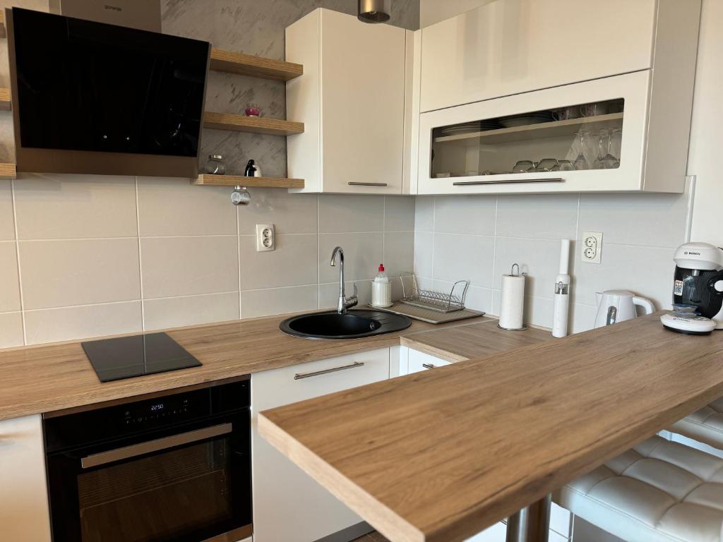 a kitchen with white cabinets and a wooden counter top at SUNRAY Apartman Požarevac in Požarevac