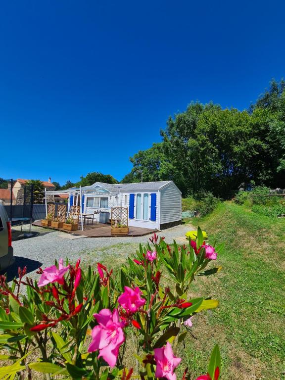 a house with pink flowers in front of it at Joli Mobil-Home avec terrain terrasse 10min du Puy duFou in LʼÉpaux