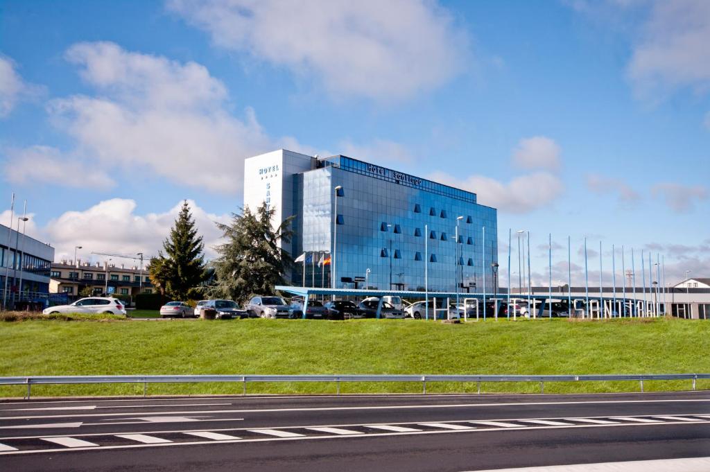 un gran edificio de cristal con coches aparcados en un aparcamiento en Hotel Auditorio Santiago & Spa, en Lugo
