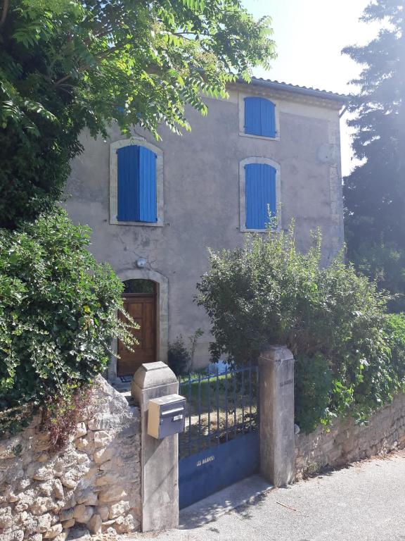 une maison dotée de fenêtres bleues et d'une boîte aux lettres en face de celle-ci dans l'établissement Maison de village provençale, à Monieux