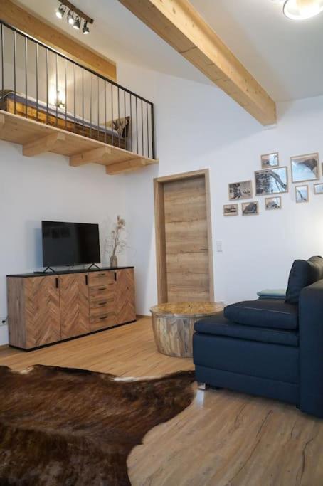a living room with a blue couch and a television at Loftwohnung Kaiserblick im Inntal - 83 qm - zentral & ruhig in Flintsbach am Inn