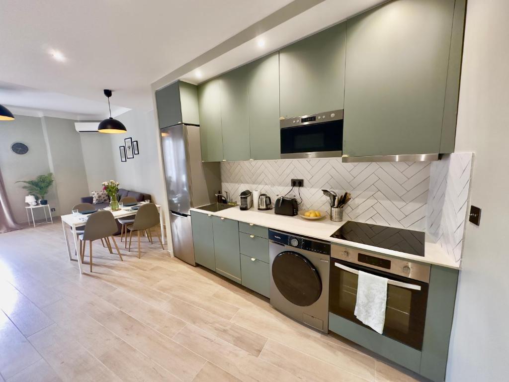 une cuisine avec des placards verts et une table avec des chaises dans l'établissement Cosy Home Cannes - Croisette, à Cannes