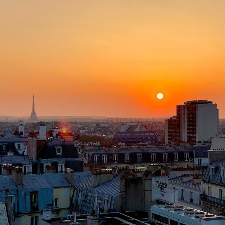 - une vue sur une ville avec le coucher du soleil en arrière-plan dans l'établissement Loft 80m2 Parking Vues magiques, à Paris