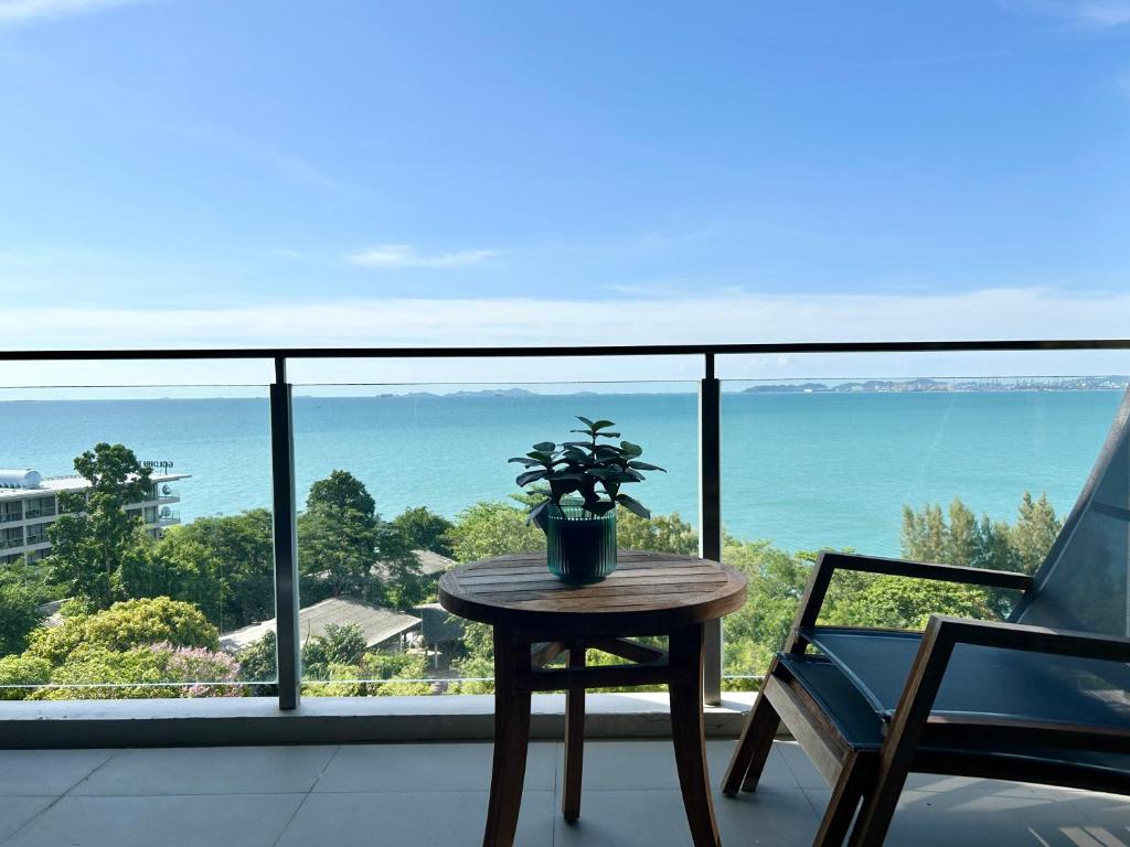 a table and a chair on a balcony with a view of the ocean at Cosy seaview two bedrooms Nakula in North Pattaya