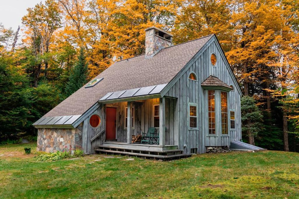 a small house with a gray roof on a field at Green Mountain base camp for year-round adventure! in Londonderry