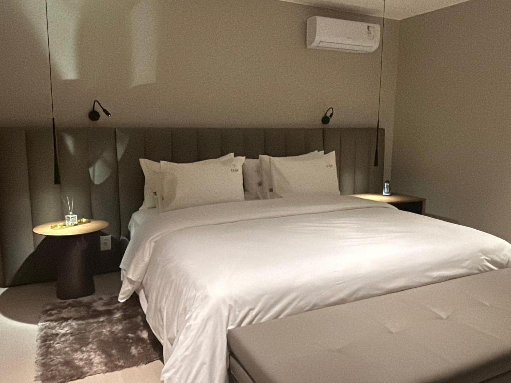 a bedroom with a large white bed and two tables at Jade Hotel Brasília in Brasilia