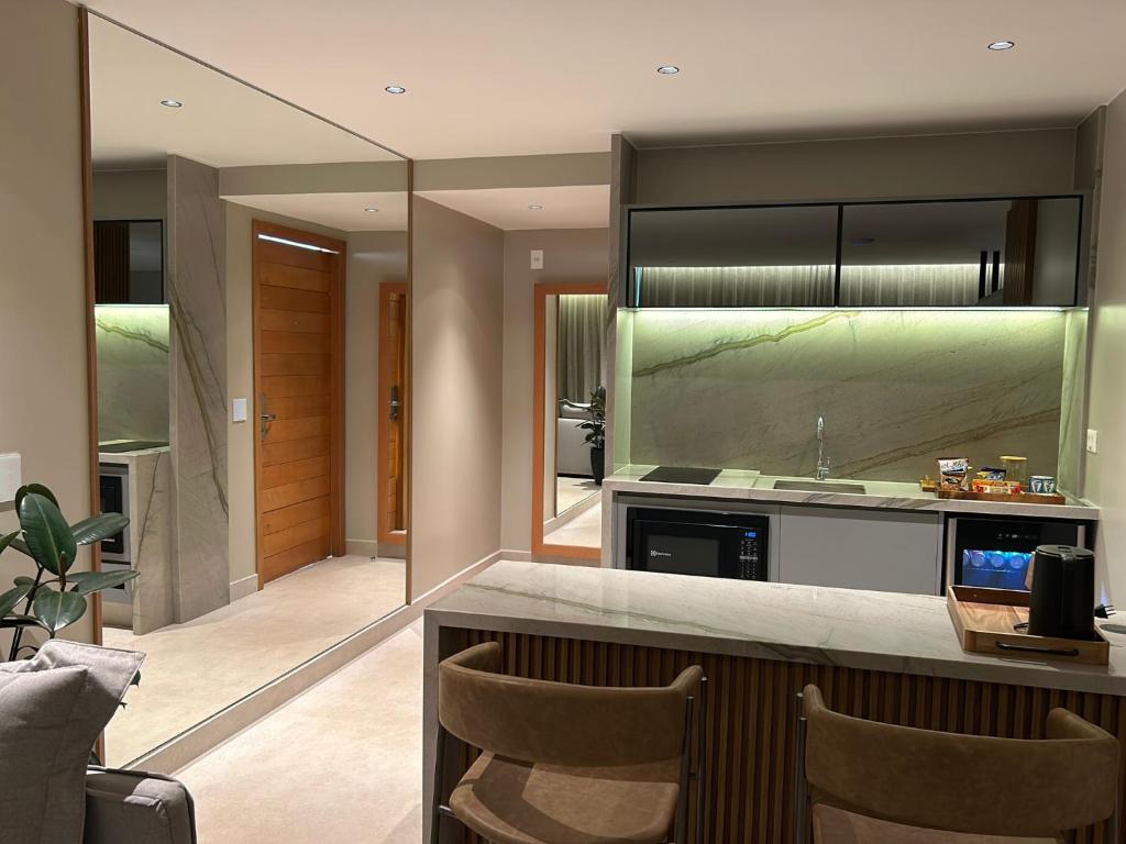 a kitchen with a counter with chairs and a sink at Jade Hotel Brasília in Brasilia