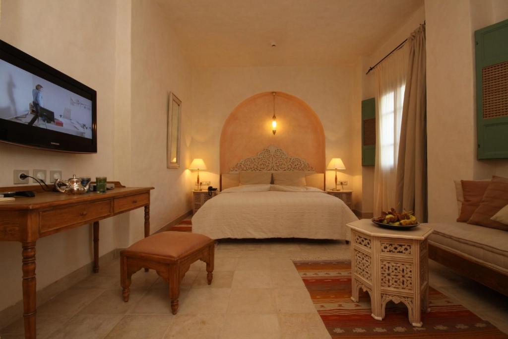 a bedroom with a bed and a tv and a couch at Dar Saida Beya in Tozeur