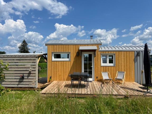 une petite maison avec une table et des chaises sur une terrasse dans l'établissement La Tiny House, La Chandeleytte, à Champdray