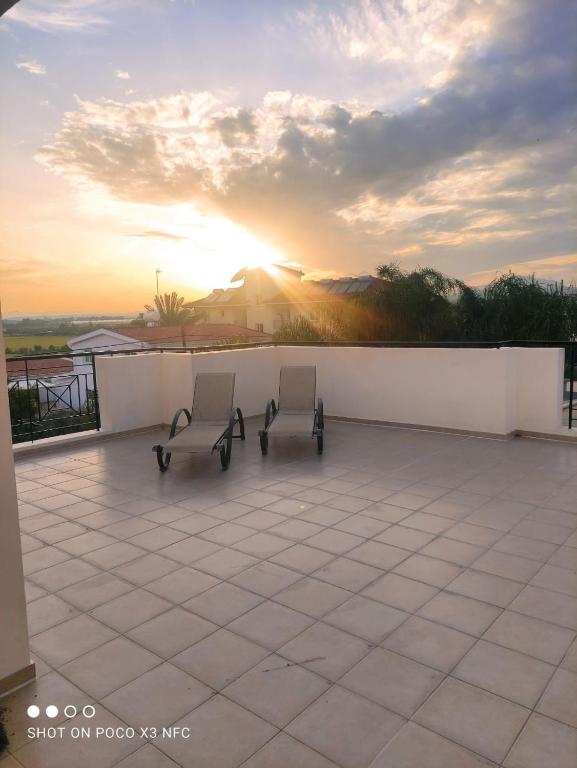 two chairs on a patio with the sunset in the background at Kiti 2 bedroom Penthouse in Kiti