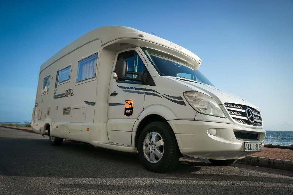 カトゥナーヤカにあるJUST CAMP IT Campervans and Motorhomes - Colombo City and Bandaranaike International Airport Arrivals Car Parkの海の横に停車した白いキャンピングカー