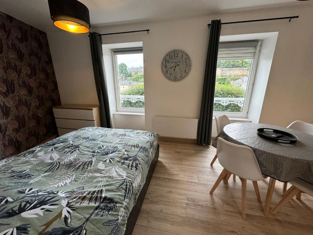 a bedroom with a bed and a table and a clock at Studio 2ème étage - Centre-ville - Local vélos disponible in Mayenne