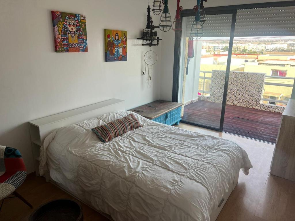 a bedroom with a bed and a window with a view at Eden in Dar Bouazza