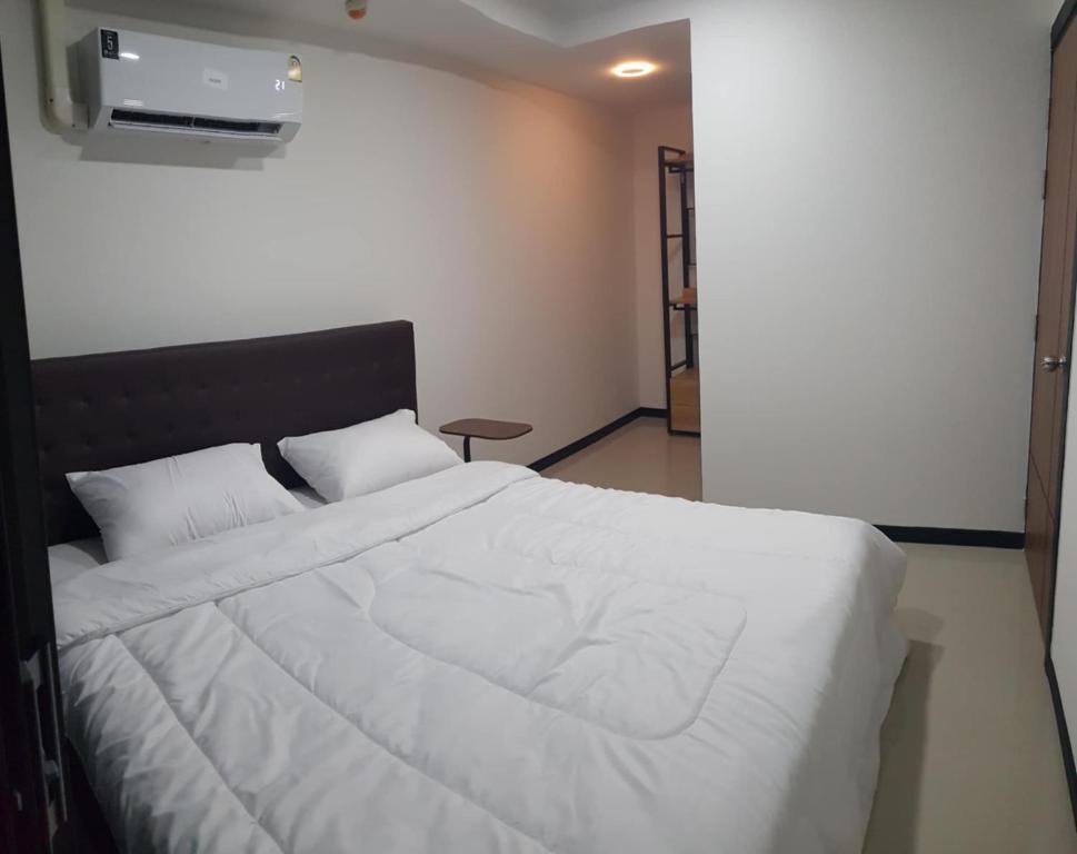 a bedroom with a white bed and a air conditioner at Rawai beach condominium 拉薇海滩酒店公寓 in Nai Harn Beach
