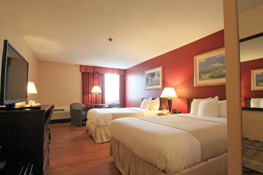 a hotel room with two beds and a flat screen tv at Fireside Inn & Suites Portland in Portland