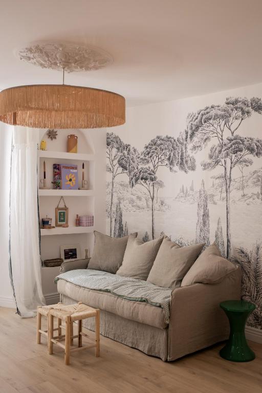 - un salon avec un canapé et des arbres sur le mur dans l'établissement Mon cocon au cœur du village et des plages, à Bandol