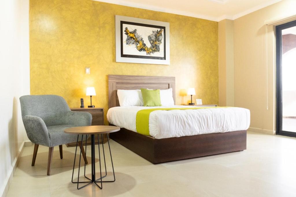 a bedroom with a bed and a chair and a table at Hotel Quinta Los Laureles in Atlixco