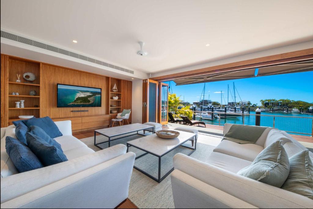 Una sala de estar con muebles blancos y una gran ventana. en Airlie Beach Marina-Front Luxury at 10 The Cove, en Airlie Beach