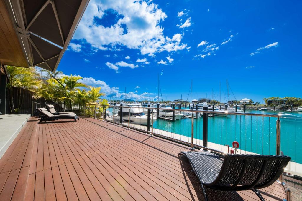 a deck with chairs and a marina with boats at Airlie Beach Marina-Front Luxury at 10 The Cove in Airlie Beach