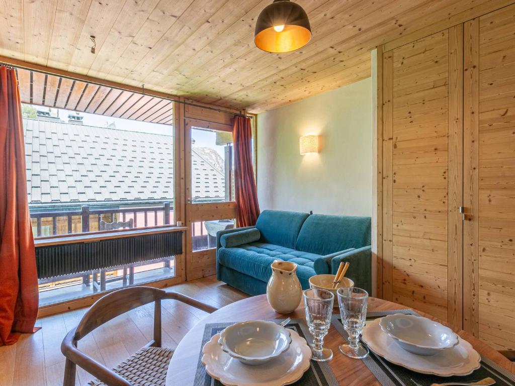 un salon avec une table et un canapé bleu dans l'établissement Studio 19m², Balcon, Accès pistes - Val d'Isère - FR-1-694-360, à Val dʼIsère