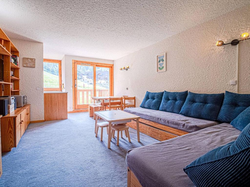 un salon avec un canapé bleu et une table dans l'établissement Valmorel: Appt 32m², skis aux pieds, balcon, casier à skis - FR-1-356-486, à Valmorel