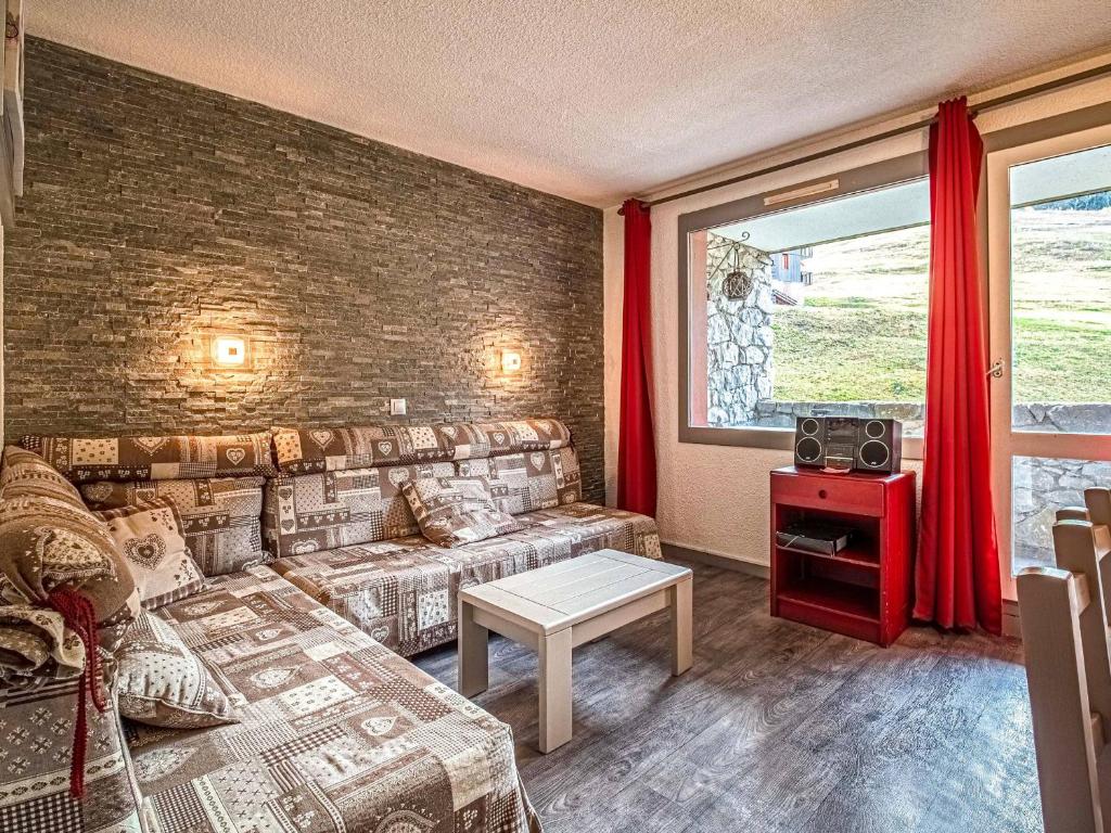 un salon avec un canapé et un mur de briques dans l'établissement Valmorel - Appartement 2 pièces avec balcon, accès pistes et animaux admis - FR-1-356-494, à Valmorel
