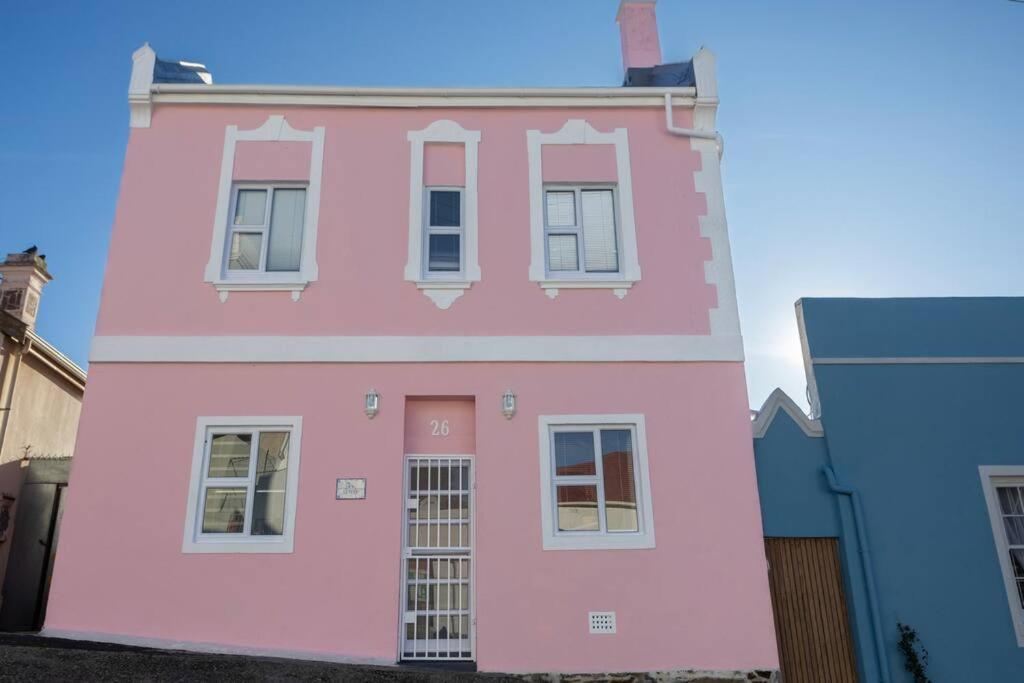 a pink house with white windows on a street at The Dolls House in Cape Town