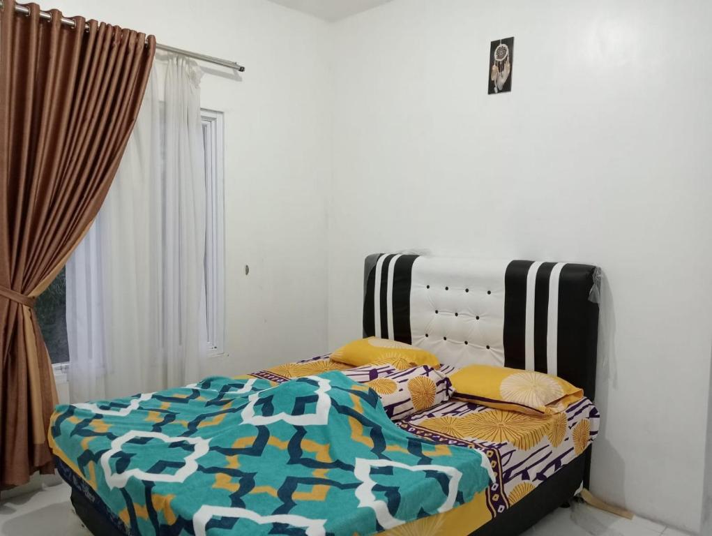 een bed met een dekbed en kussens in een slaapkamer bij Villa Putih in Cisarua