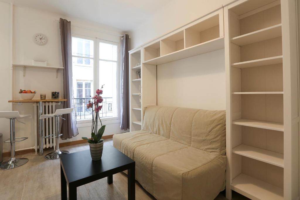 a living room with a couch and shelves at Renovated Studio for 2 in Paris