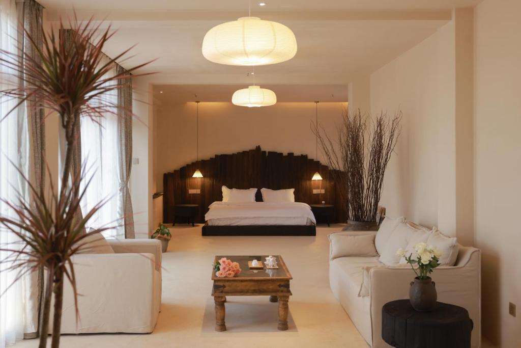 ein Wohnzimmer mit einem Bett, einer Couch und einem Tisch in der Unterkunft YSN Hill Breeze Retreat 云山南 玉龙雪山园林观景酒店 丽江古城束河白沙古镇店 in Lijiang