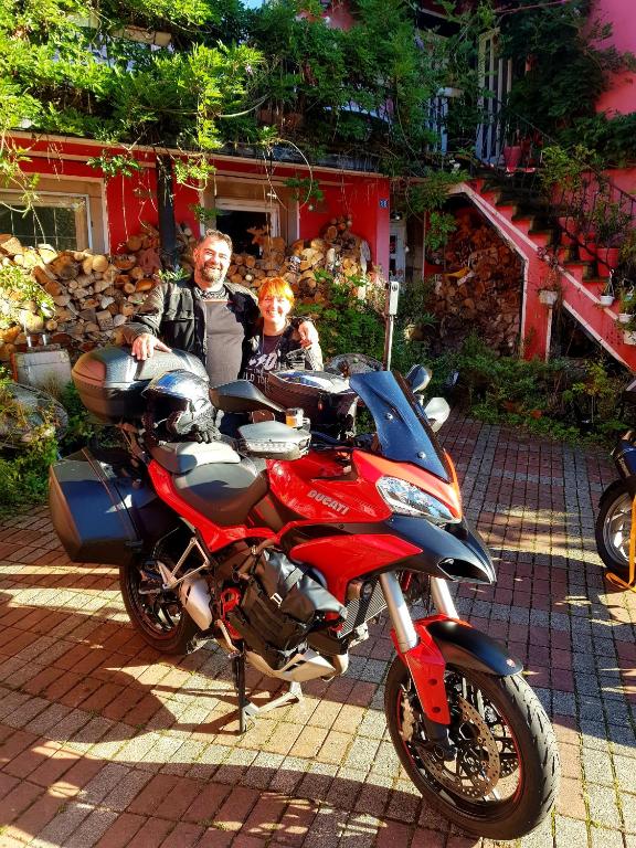 un homme et une femme debout à côté d'une moto rouge dans l'établissement Tilly's B&B and apartment house, au Hohwald