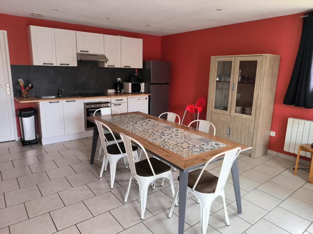 a kitchen with a wooden table and white cabinets at Les Champs De La Mer in Auberville-la-Renault