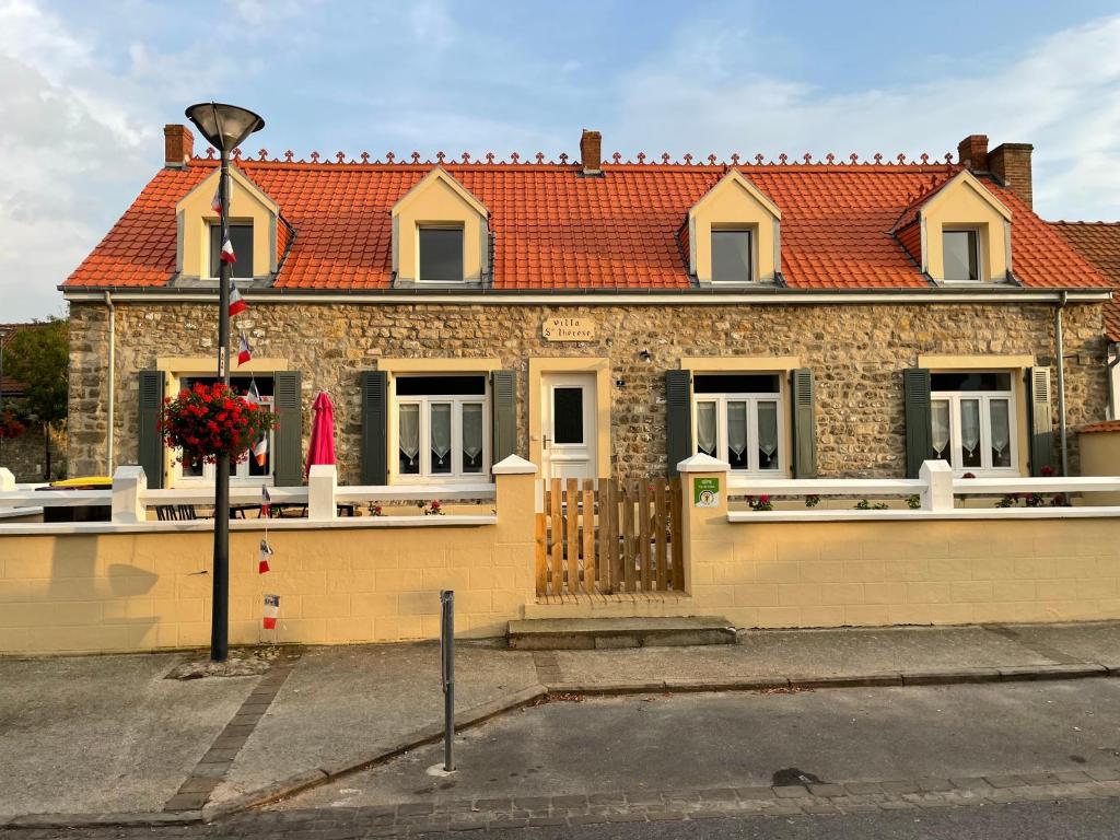 une maison en briques avec un toit rouge dans une rue dans l'établissement Wissant Villa Sainte Thérèse, à Wissant