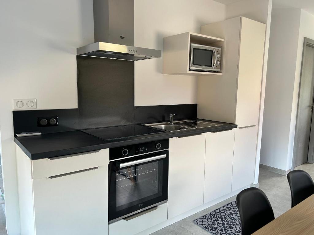 une cuisine avec une cuisinière et un micro-ondes dans l'établissement Gîte neuf en duplex tout confort, à Ribeauvillé