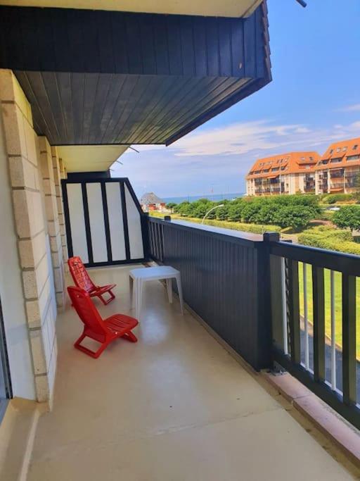 - un balcon avec deux chaises rouges et une table dans l'établissement Plein Soleil, Appartement 2 chambres, Balcon et vue mer, à Villers-sur-Mer