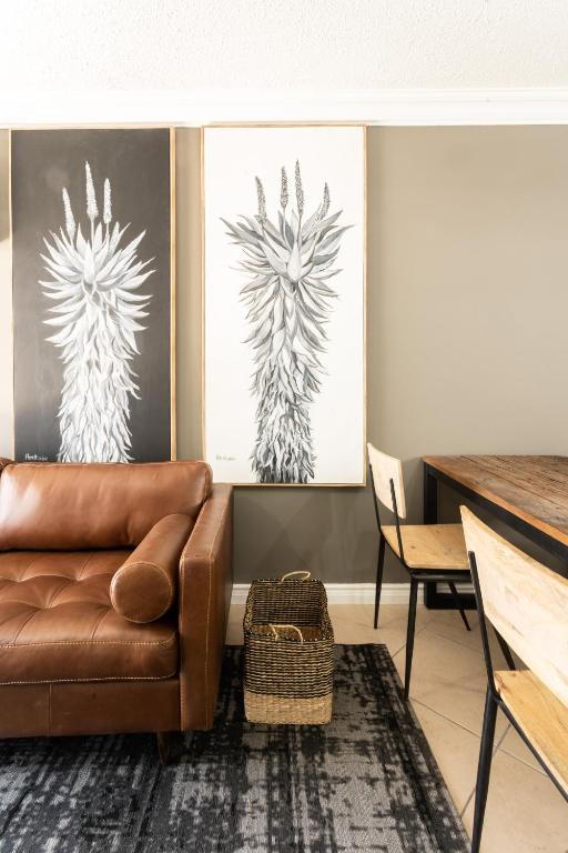 a living room with a brown couch and two paintings at Avemore Jan Cats No 3 in Stellenbosch