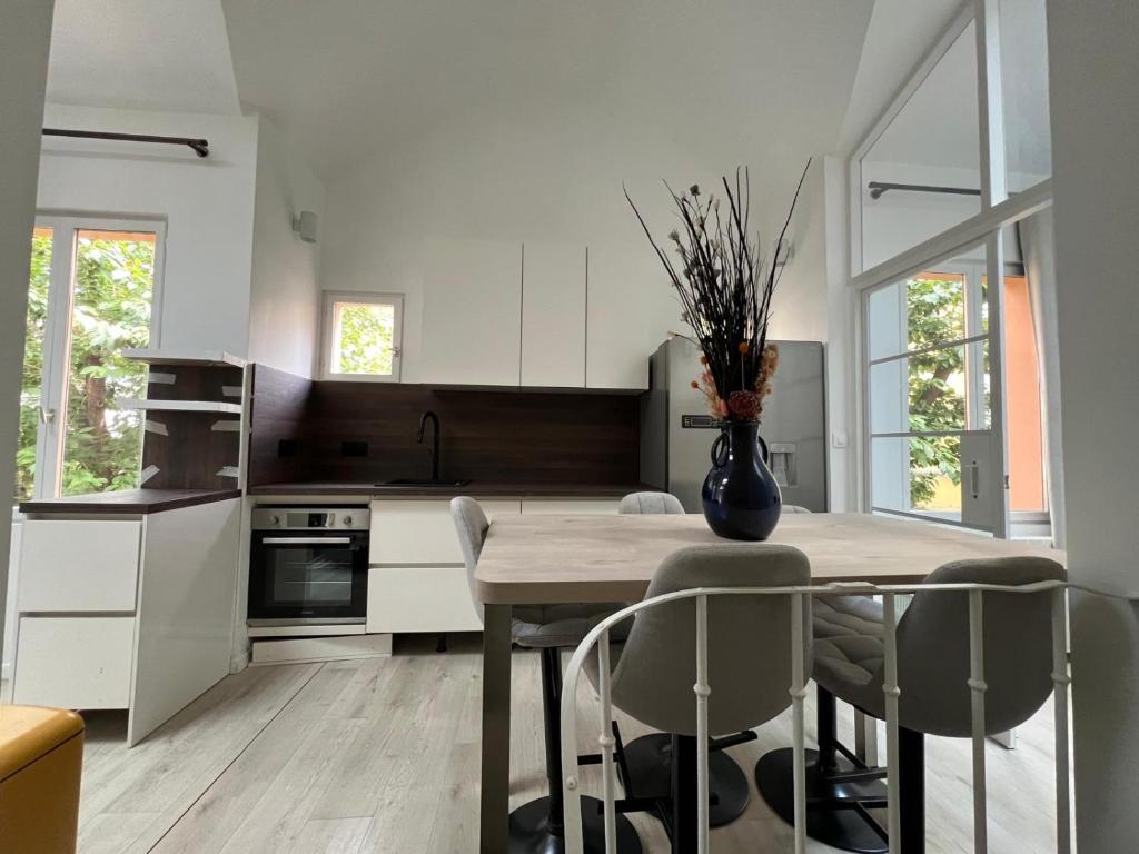 une cuisine avec une table, des chaises et un vase. dans l'établissement Duplex plein Sud, à Paris