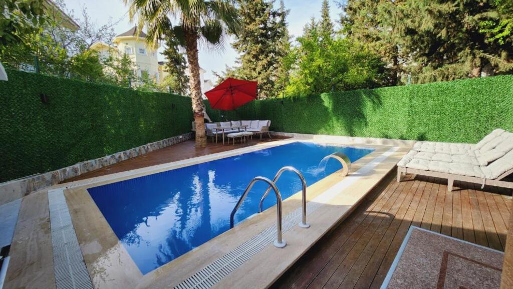 a swimming pool with a red umbrella next to a fence at Villa De Papel in Belek