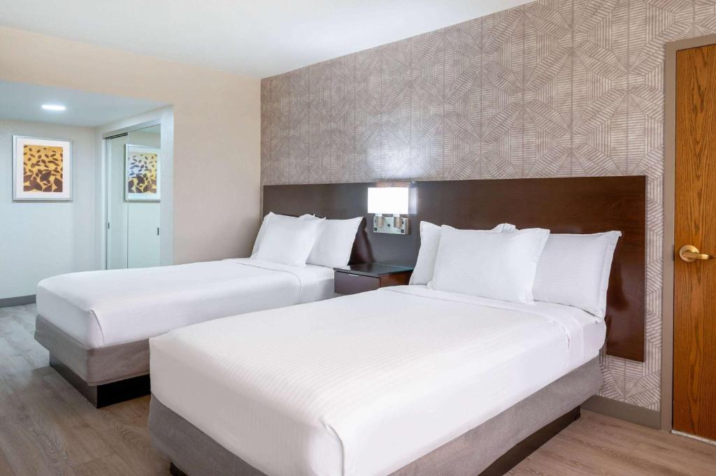 two beds in a hotel room with white pillows at Wyndham Indianapolis Airport in Indianapolis