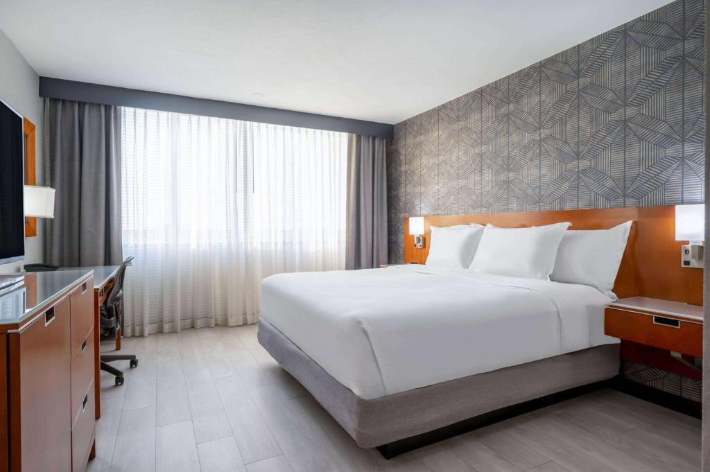 a bedroom with a large white bed and a desk at Wyndham Indianapolis Airport in Indianapolis