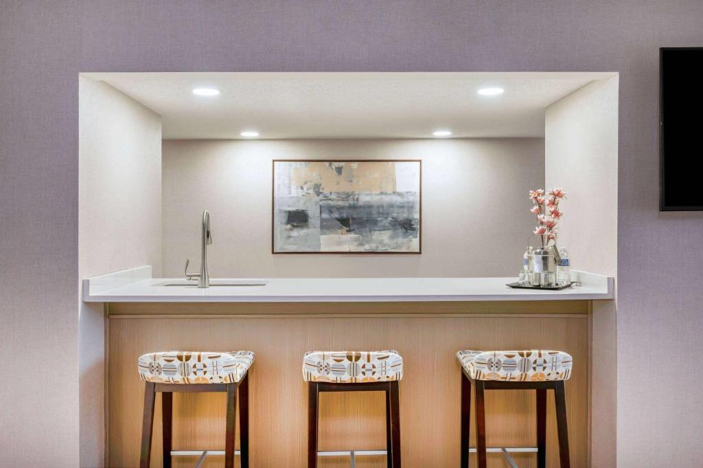 a bar with two stools under a counter with a sink at Wyndham Indianapolis Airport in Indianapolis