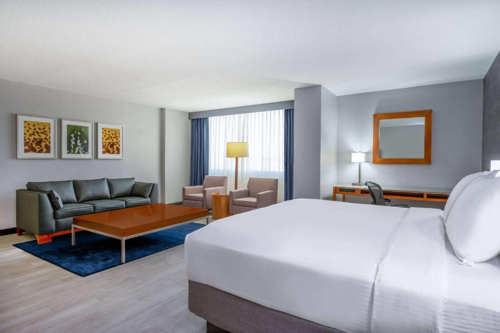 a hotel room with a bed and a living room at Wyndham Indianapolis Airport in Indianapolis