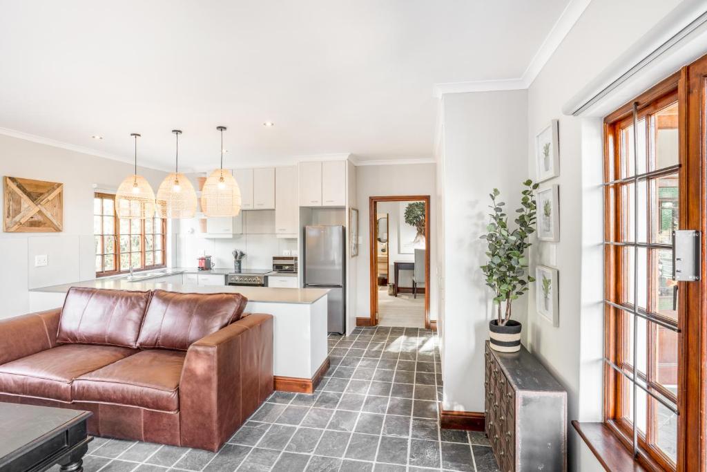 a living room with a couch and a kitchen at Avemore Olive Le Verger in Stellenbosch