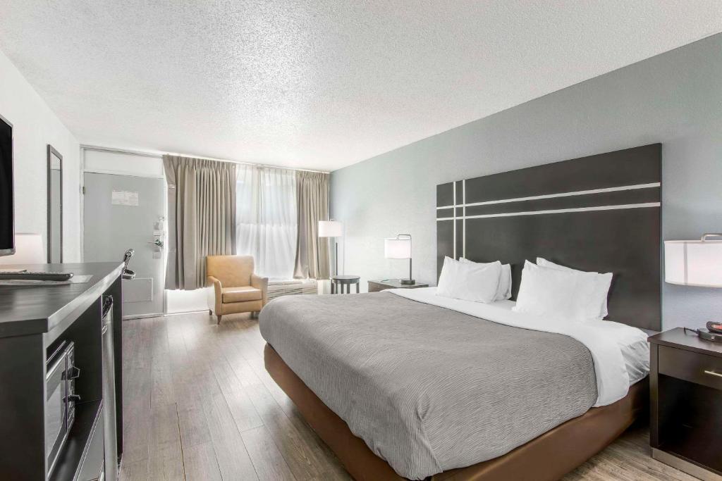 a hotel room with a large bed and a chair at Quality Inn & Suites Hardeeville - Savannah North in Hardeeville