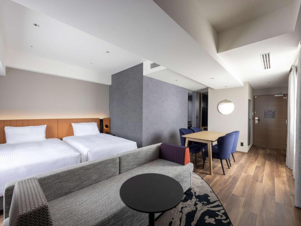a hotel room with a bed and a couch and a table at Novotel Nara in Nara