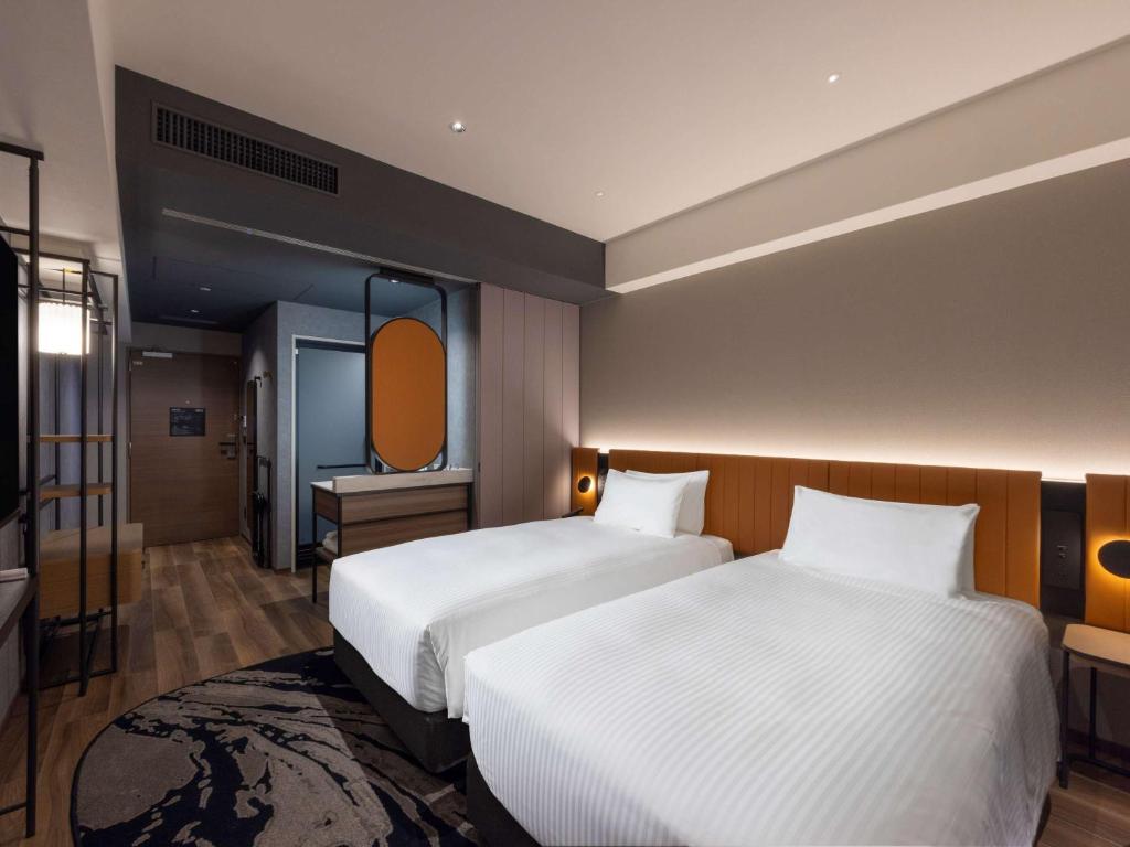 a hotel room with two beds and a mirror at Novotel Nara in Nara