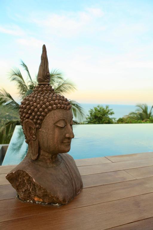 a statue sitting on a table next to a pool at House of Rising Sun in Thong Nai Pan Noi