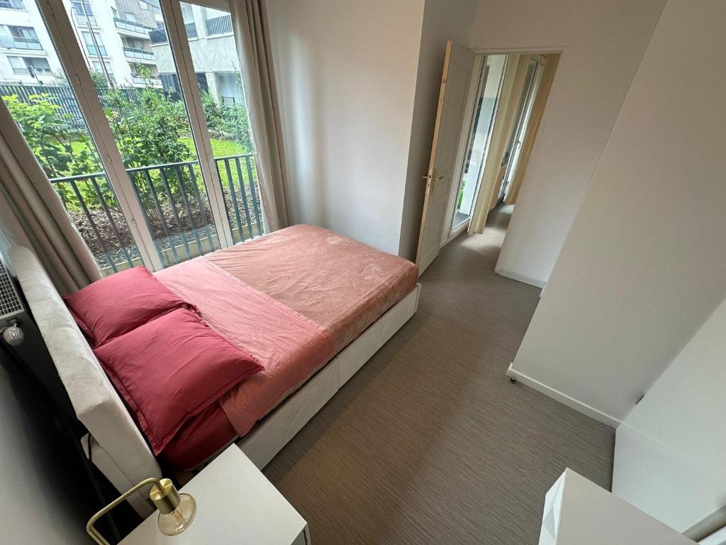 - une petite chambre avec un lit et une grande fenêtre dans l'établissement Home in Paris, à Bezons